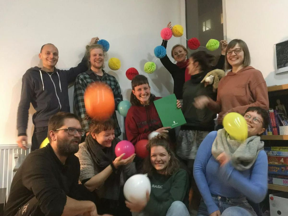 Eine Gruppe Menschen mit einem Kreditvertrag und Luftballons